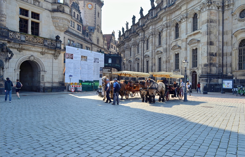 4 - A view in the historic center of Dresden, Germany, featuring horse-drawn carriages stationed near grand Baroque-style historic architecture
